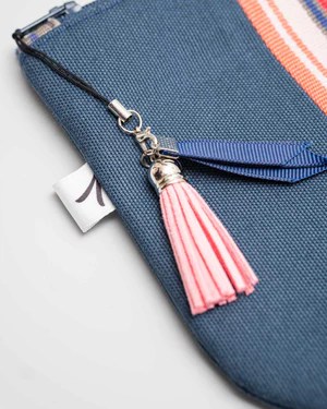 pompon en suedine rose accroché à la fermeture éclair d'un sac bleu