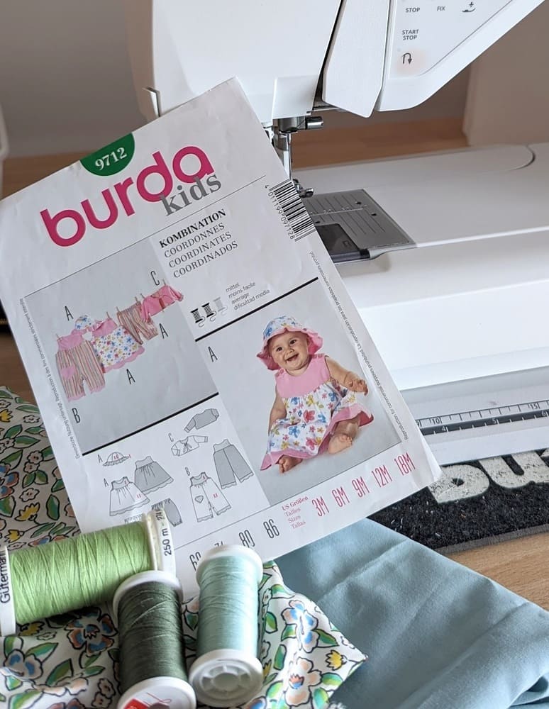 Du tissu et du fil vert, un patron de couture robe et cahapeau bébé