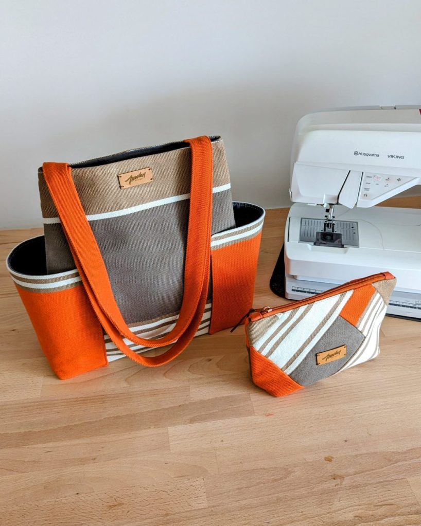 Sac et trousse en toile rayée orange, gris, blanc, près d'une machine à coudre.